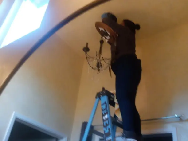 Electrician installing a chandelier in a Town 'n' Country residence